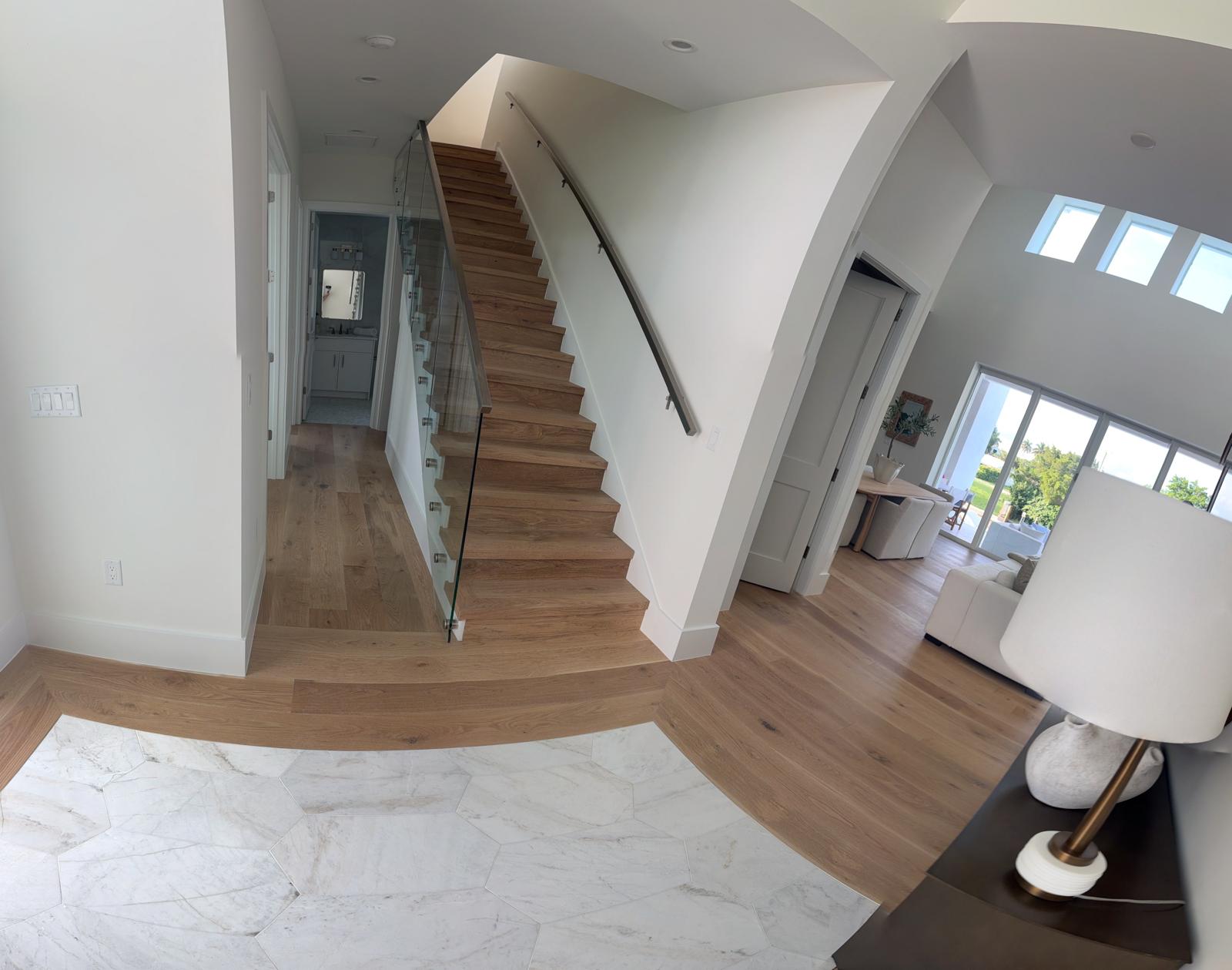 Wide-plank white oak flooring and matching staircase treads in a Naples home by Topline Flooring
